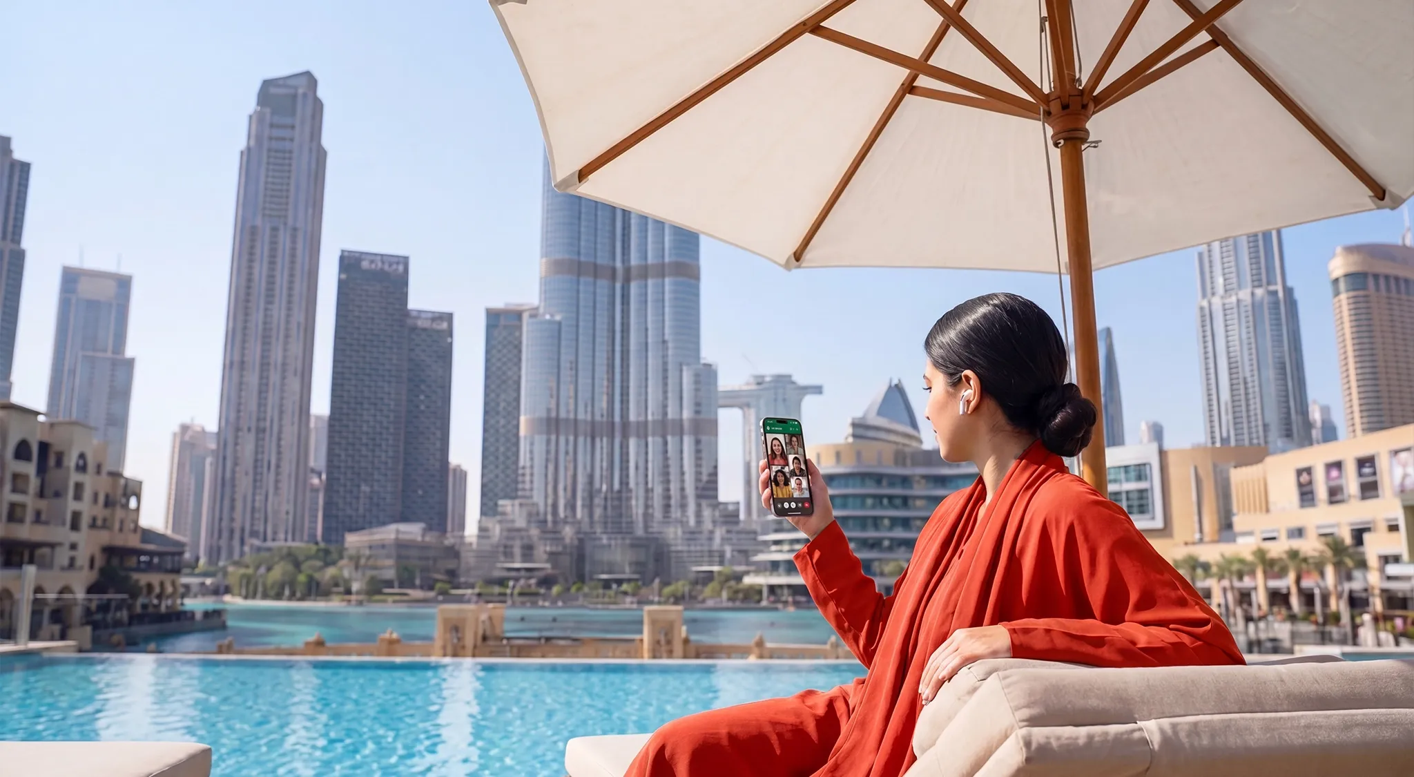A woman sitting by the lake in Dubai and making a WhatsApp video call